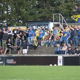 Mehrere Fans von Atlas Delmenhorst feuern ihre Mannschaft während eines Spiels an.