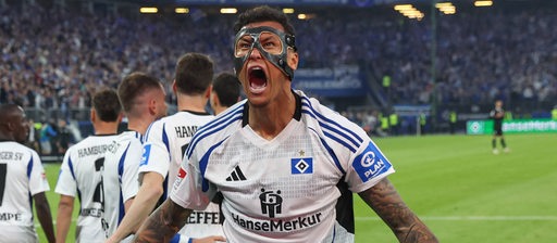 Der Fußball-Profi des Hamburger SV Davie Selke trägt eine schwarze Maske im Gesicht und schreit mit martialischer Geste seinen Torjubel hinaus.