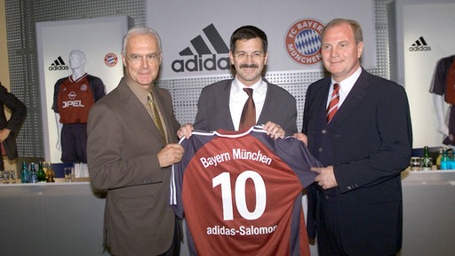 Franz Beckenbauer, Herbert Hainer und Uli Hooeß zeigen im Jahr 2001 ein Bayern-Trikot, auf dem "10 adidas-Salomon" steht.