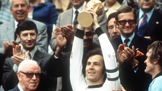Fußball-Legende Franz Beckenbauer reckt nach dem Gewinn der WM 1974 den goldenen Pokal hoch.
