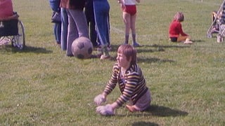 Eine Person mit Behinderung trägt Torwarthandschuhe und läuft einem Fußball nach