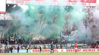 Im Werder-Fanblock im Stadion von Union Berlin werden grün-weiße Rauchtöpfe und Feuerwerksraketen gezündet.