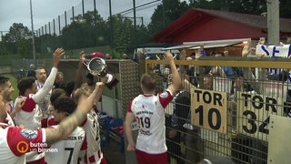Die Spieler des Bremer SV feiern mit ihrem Pokal am Zaun gemeinsam mit den Fans den Sieg.