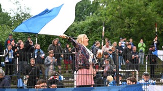 Ein Fan des Bremer SV wchwenkt eine Fahne.