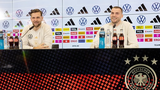 Die ehemaligen Sturmpartner Marvin Ducksch und Niclas Füllkrug bei der DFB-Pressekonferenz lachend wiedervereint.