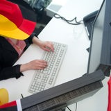 Eine Frau in Fankleidung sitzt am 06.06.2014 in einem zur Fußball-WM mit Deutschlandfahnen geschmückten Büro in Berlin. 