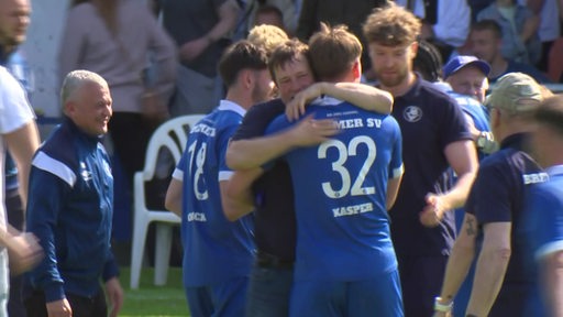 Spieler und Trainer des Bremer SV umarmen sich nach dem Spiel.