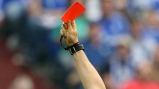 Ein Schiedsrichter zeigt eine Rote Karte.