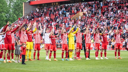 Die Spieler von Union Berlin feiern vor ihrer Kurve einen Heimsieg.