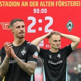 Werder-Kapitän Marco Friedl applaudiert, während Amos Pieper die Hände hinter dem Kopf verschränkt.