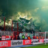 Im Werder-Fanblock im Stadion von Union Berlin brennt Pyrotechnik und die Tribüne ist grün-weißen Rauch eingehüllt.