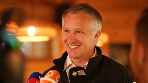 Werder-Sportchef Frank Baumann lächelt während eines TV-Interviews am Rande des Trainingslagers.