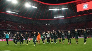 Die Werder-Spieler jubeln aufgereiht in der Münchner Arena vor dem Bremer Fanblock nach dem Sieg gegen die Bayern.