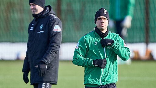 Werder-Stürmer Rafael Borré am Rande des Trainings, Coach Ole Werner steht im Hintergrund.