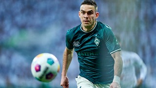Werder-Stürmer Rafael Borré fixiert im Spurt den Fußball vor ihm in der Luft.