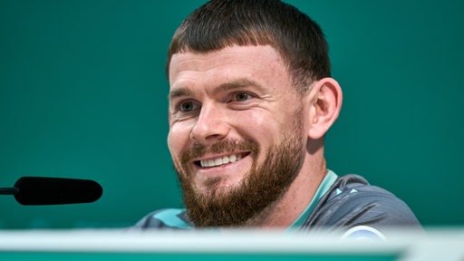 Werder-Stürmer Oliver Burke strahlt während einer Pressekonferenz.