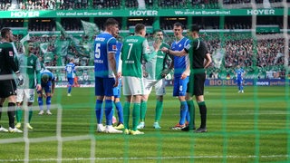 Werder-Spieler um Marvin Ducksch diskutieren mt dem Schiedsrichter über eine Elfmeter-Rücknahme im Spiel gegen Darmstadt 98.