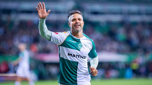 Der lachende Diego joggt im Werder-Trikot durchs Werder-Stadion und winkt den Fans.