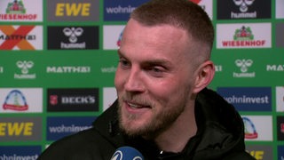 Werder-Stürmer Marvin Ducksch lächelt bei einem Interview nach dem Sieg gegen Stuttgart.