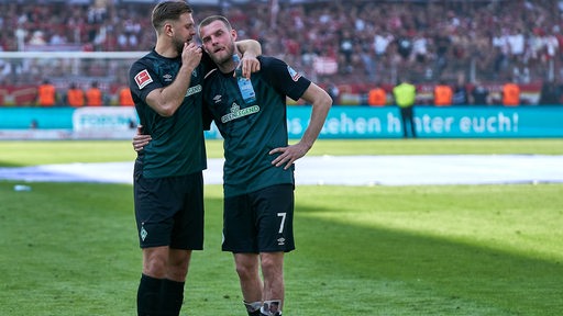 Die Werder-Stürmer Marvin Ducksch und Niclas Füllkrug stehen nach dem letzten Spieltag auf dem Spielfeld nahe beieinander und reden.