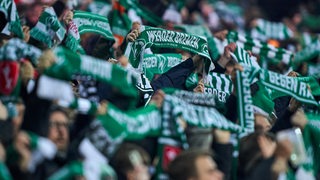 Werder-Fans halten im Weser-Stadion ihre Fan-Schals hoch.