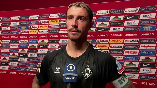 Werder-Kapitän Marco Friedl steht konsterniert vor einer Werbewand beim Interview nach der Niederlage gegen Freiburg.