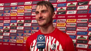 Freiburg-Fußballer Maximilian Philipp steht strahlend vor einer Werbewand beim Interview nach dem Sieg gegen Bremen.