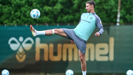 Werder-Kapitän Marco Friedl streckt beim Training sein rechtes Bein weit aus, um einen Ball in der Luft zu treffen.