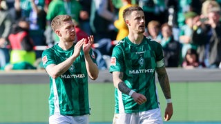 Werders Fußballer Mitchell Weiser und Marco Friedl gehen nach Spielende gegen Bochum über den Platz.