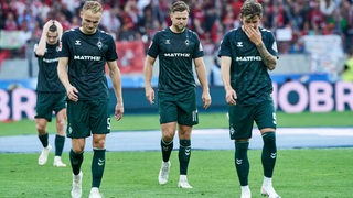 Enttäuschte Werder-Spieler um Niclas Füllkrug stehen nach der Niederlage gegen Freiburg mit hängenden Köpfen auf dem Rasen.