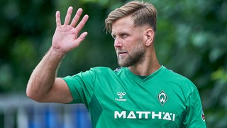 Werder-Stürmer Niclas Füllkrug winkt freundlich am Rande des Trainings.