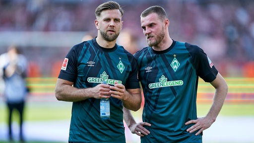 Die Werder-Stürmer Niclas Füllkrug und Marvin Ducksch stehen nach dem Saisonfinale auf dem Spielfeld im Gespräch zusammen.