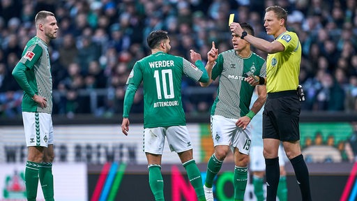 Werder-Profi Leonardo Bittencourt ärgert sich über den Schiedsrichter, der ihm die Gelbe Karte zeigt.