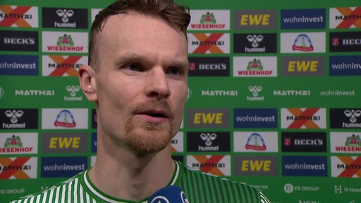 Werder-Spieler Christian Groß steht nach dem Remis gegen Darmstadt vor einer grünen Werbewand beim Interview.