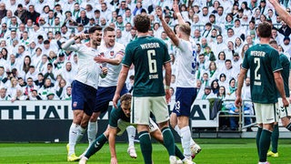 Frustrierte Werder-Spieler schauen zu, wie Heidenheimer Spieler im Weser-Stadion ihren Treffer bejubeln.