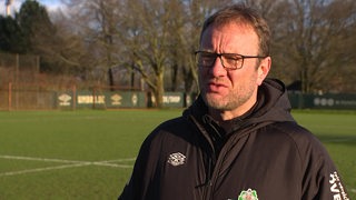 Werder-Trainer Thomas Horsch im Sonnenlicht auf dem Trainingsplatz beim Interview.