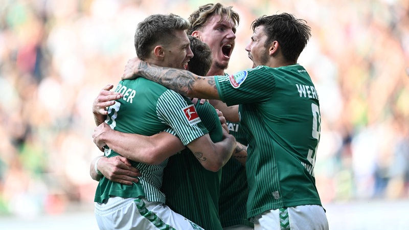 Werder-Spieler umarmen Torschütze Jens Stage und bejubeln gemeinsam seinen Treffer.