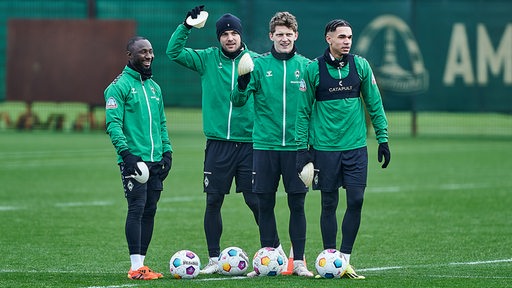 Werder-Spieler Naby Keita steht lachend beim Training neben seinen Mitspielern Cimo Röcker, Jens Stage und Justin Njinmah.