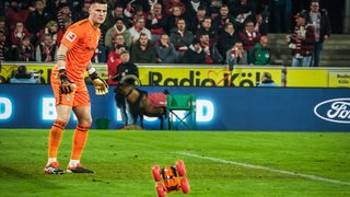 Werder-Torwart Michael Zetterer schaunt erstaunt, als neben sich im Kölner Stadion ein rotes ferngesteuertes Auto auf den Rasen geworfen wird.