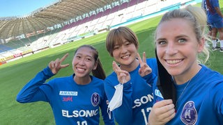 Ex-Werder-Spielerin Cindy König posiert mit ihren japanischen Teamkolleginnen im leeren Stadion für ein Selfie.
