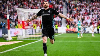 Werder-Torschütze Oliver Burke rennt mit ausgebreiteten Armen nach seinem Treffer gegen Stuttgart zu den Bremer Fans.