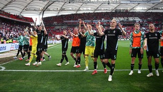 Die Fußball-Spieler von Werder Bremen jubeln nach dem Sieg im Stuttgarter Stadion vor der Werder-Fantribüne.