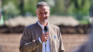 Werders Geschäftsführer Tarek Brauer steht dem Trainingsgelände und spricht in ein Mikrofon