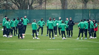 Werder-Spieler stehen während des Trainings im Kreis um Trainer Ole Werner herum und hören zu.