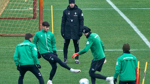 Werder-Trainer Ole Werner beobachtet eine Aufwärmübung mit Ball seiner Spieler während des Trainings.