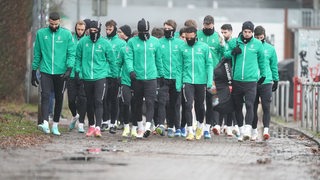 Die Spieler von Werder Bremen gehen gemeinsam den Weg hinunter zum Trainingsplatz.