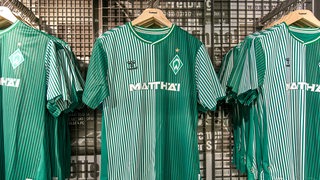 Neue, grün-weiß gestreifte Werder-Trikots hängen auf Kleiderbügeln im Fanshop.