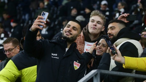 Stuttgarts Stürmer Deniz Undav macht nach dem Spiel gegen Frankfurt ein Selfie mit Fans vor der Kurve.