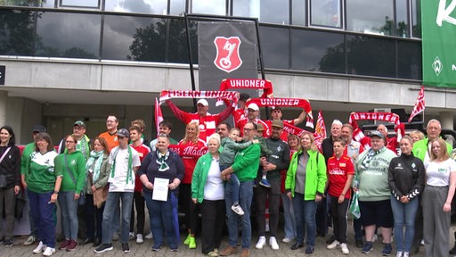 Werder-Fans und Union-Berlin-Fans stehen gemeinsam bei einer Fan vor dem Weser-Stadion zum Gruppenbild.