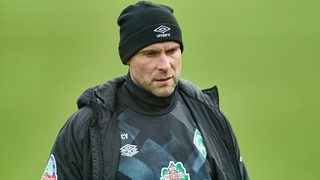 Werder Torwart-Trainer Christian Vander trägt eine schwarze Wollmütze und verlässt den Trainingsplatz.